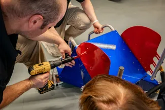 A person drilling rivets into a wheelchair assembly