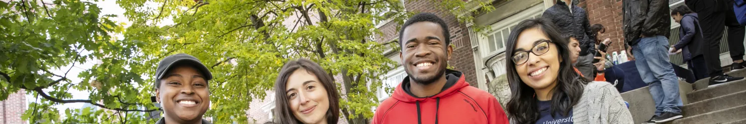 Group of graduate students participating in the University Center of Exemplary Mentoring pose in front of Coble Hall.